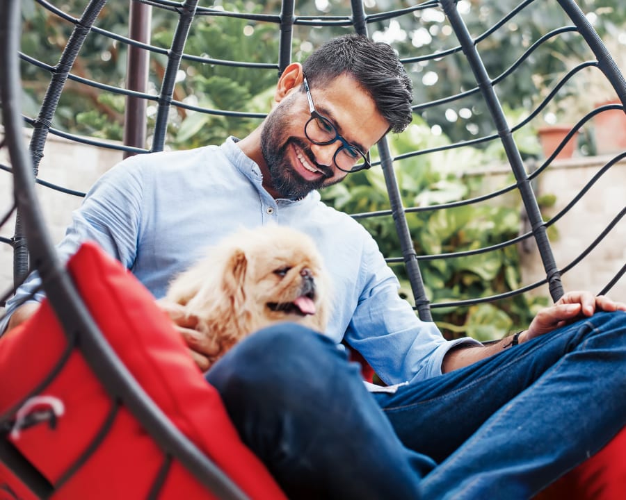 A man and a small dog sit outside in a chair.